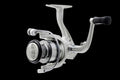 A silver Denali Lite spinning fishing reel on a black background