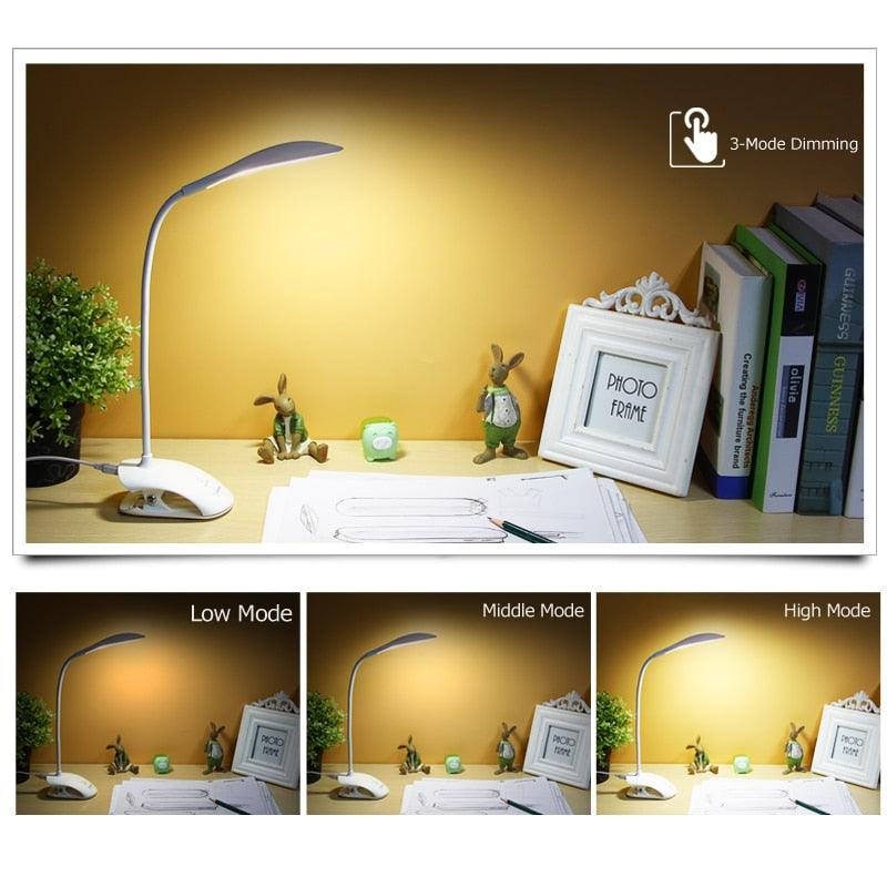 Blue clip-on LED desk lamp attached to a table edge illuminating a book.