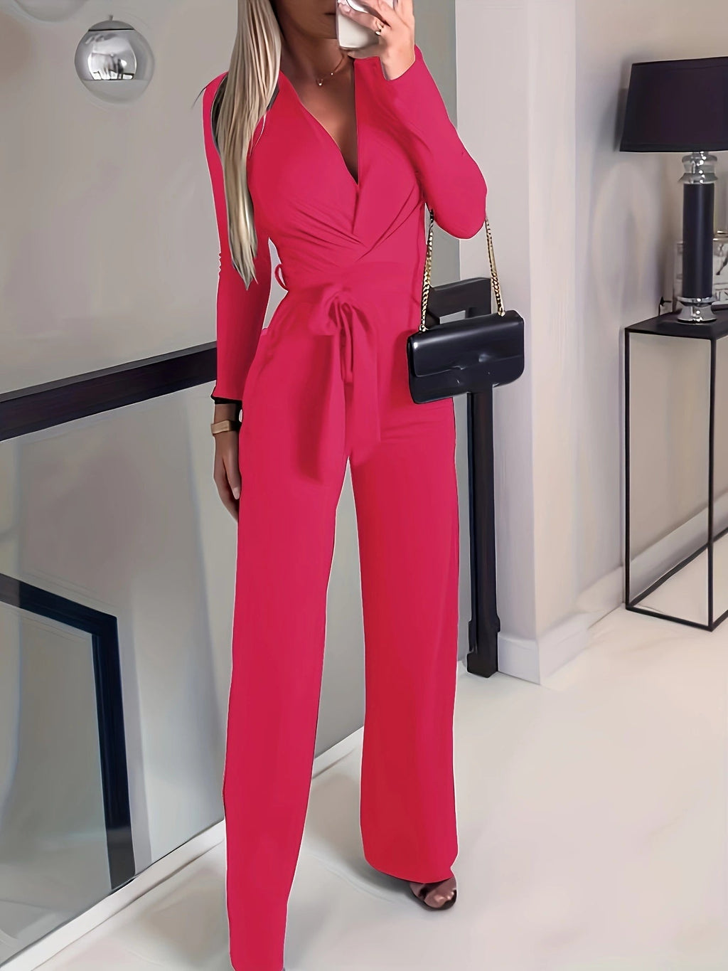 A woman wearing a vibrant red long-sleeve jumpsuit with a V-neck and a tie-waist detail, viewed from the front and back.
