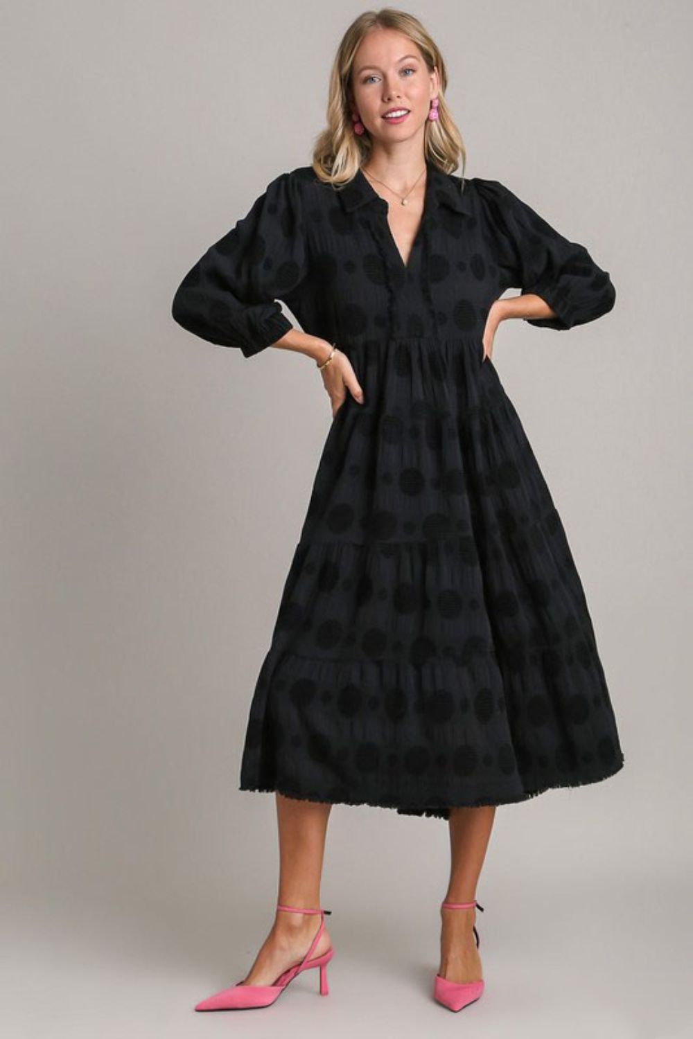 Woman wearing a black midi dress with dotted jacquard pattern and ruched waist