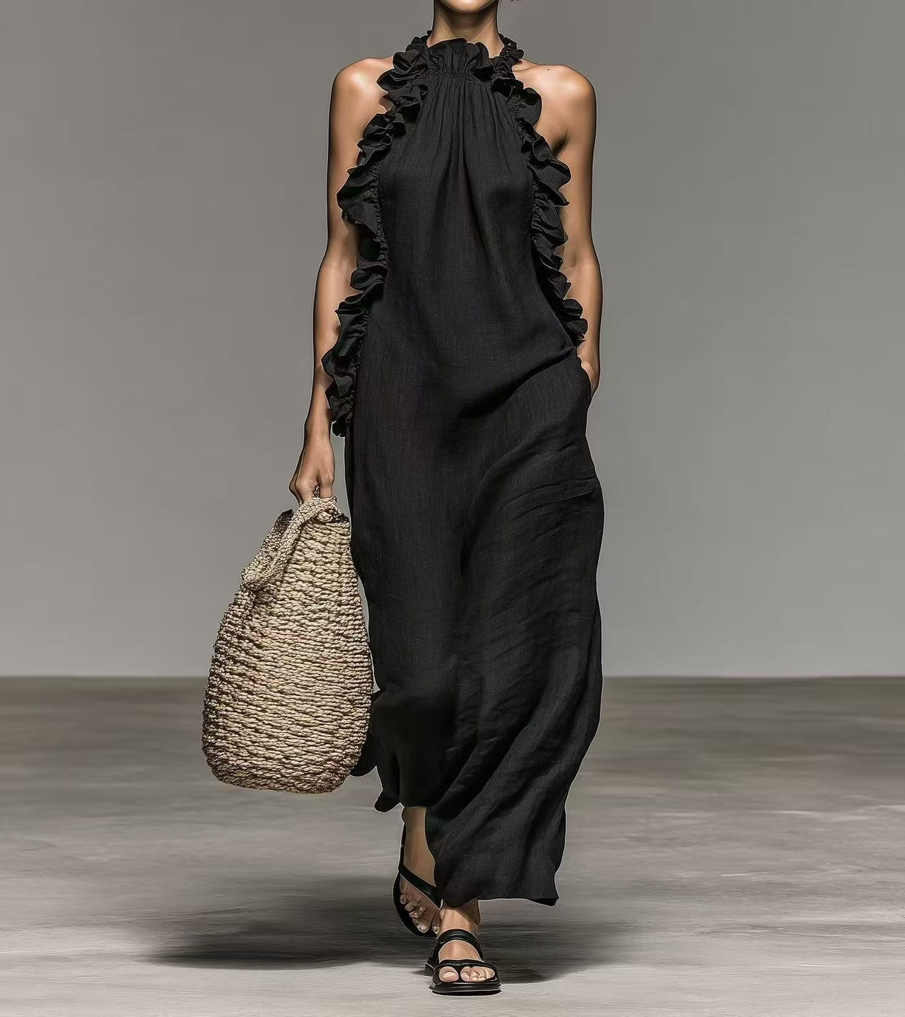 Model wearing a black, loose-fit, sleeveless halter neck maxi dress with ruffled detailing and side pockets.