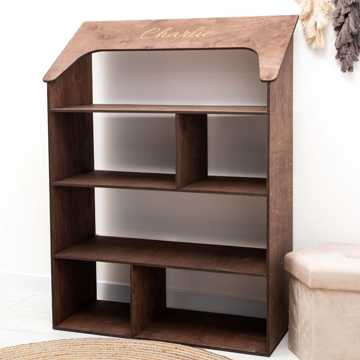 A gender-neutral, house-shaped Montessori bookcase in a bright nursery setting for toy and book storage.