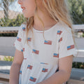 A girl wearing a casual, patriotic red, white, and blue flag print ribbed bamboo t-shirt dress with a relaxed fit.