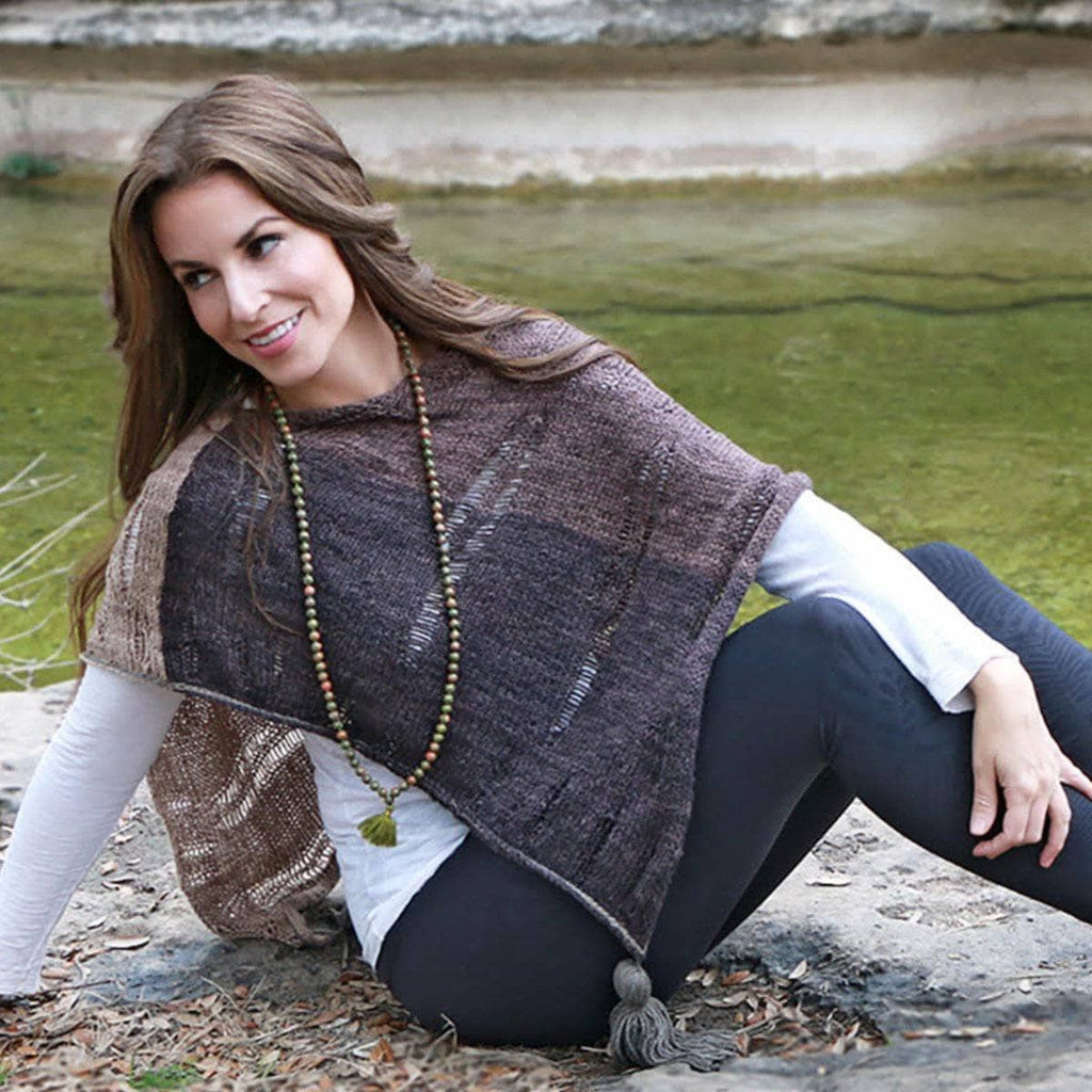 A lightweight knitted poncho made with DK weight recycled silk yarn, displayed as a fashion accessory.