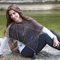 A lightweight knitted poncho made with DK weight recycled silk yarn, displayed as a fashion accessory.