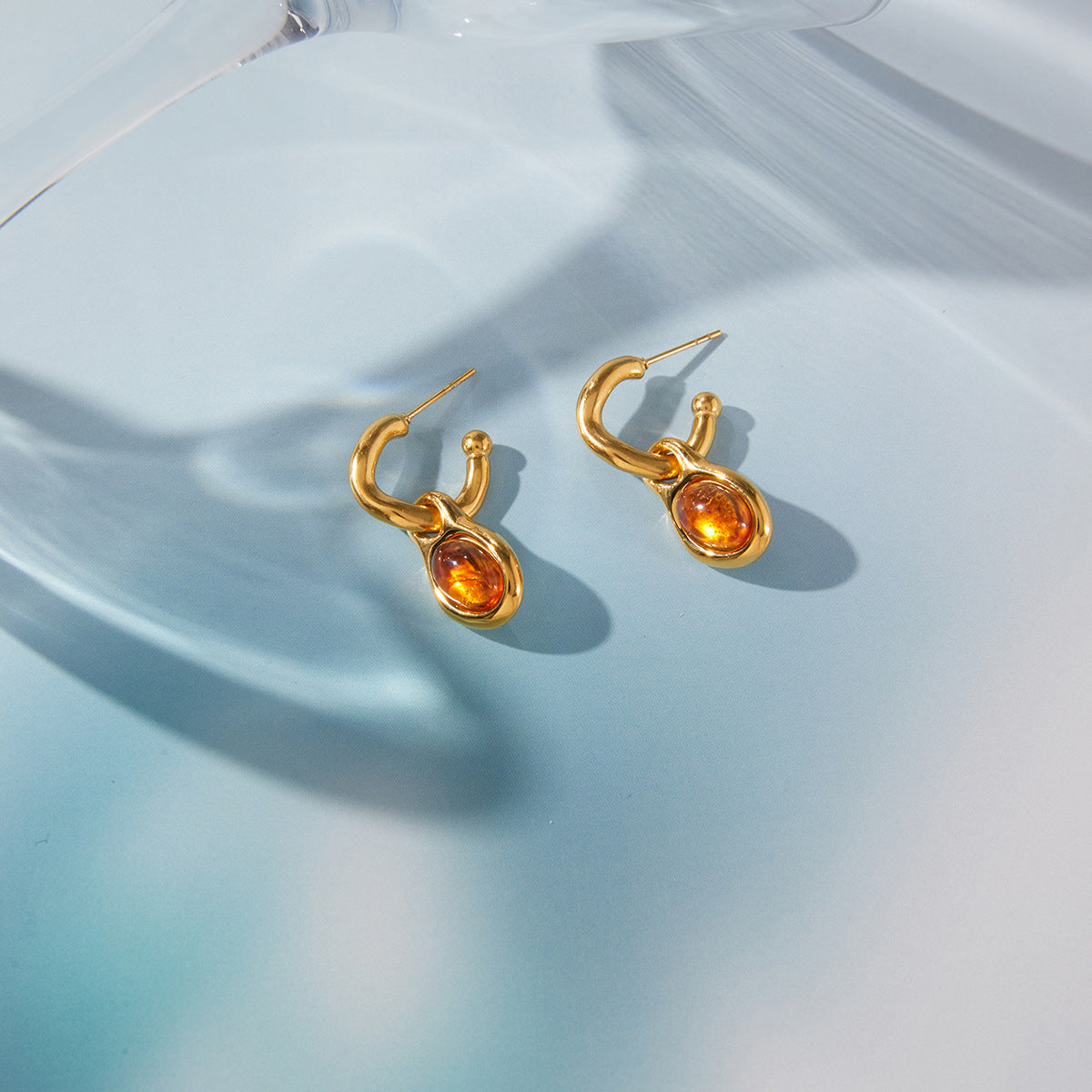 Minimalist amber resin geometric drop earrings with gold-tone stainless steel hardware.