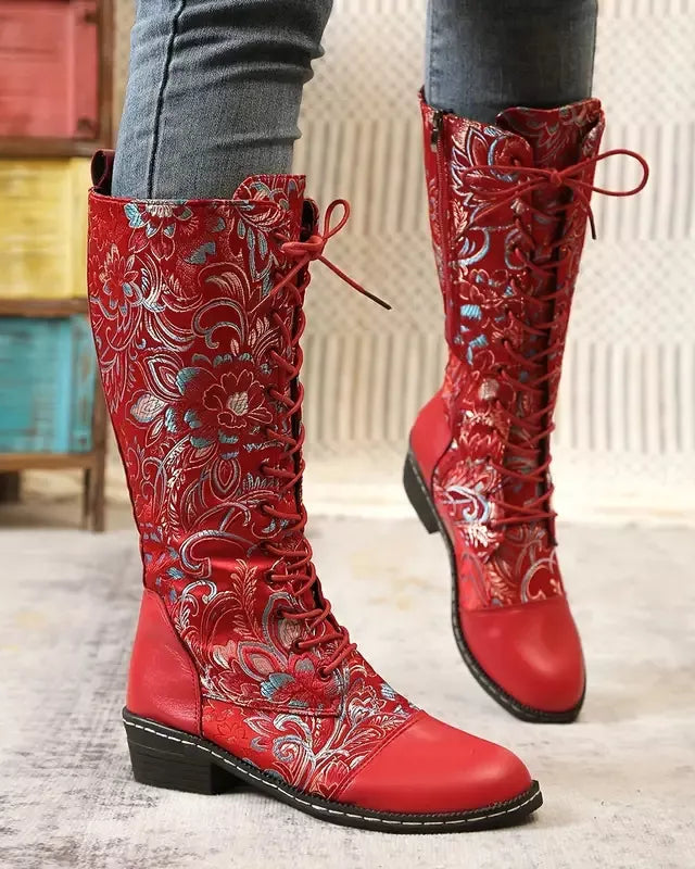 Red embroidered knee-high boots on a light wooden floor.