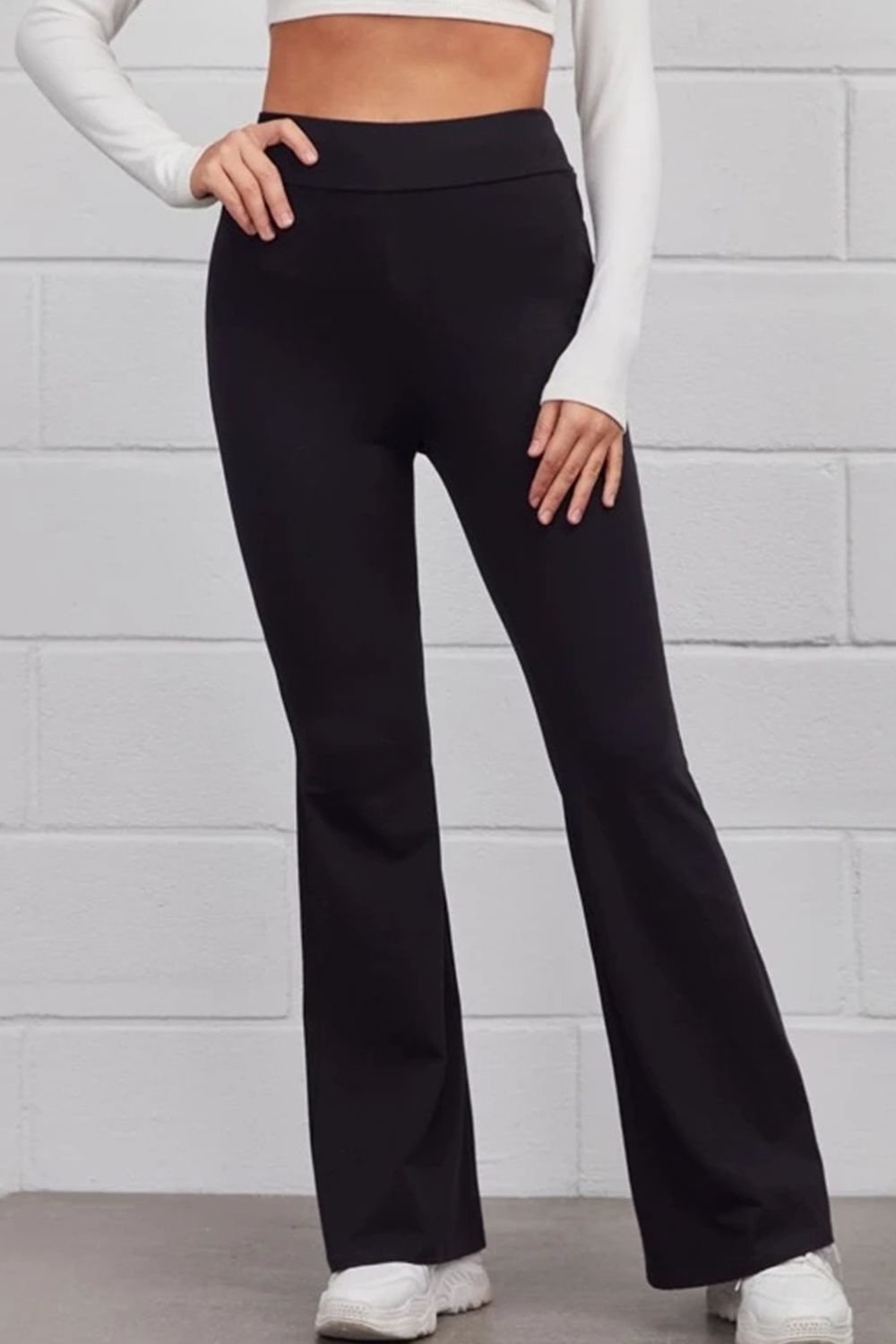 A pair of solid black pull-on flared pants shown on a model, featuring a high-rise waist and a full-length flared silhouette.
