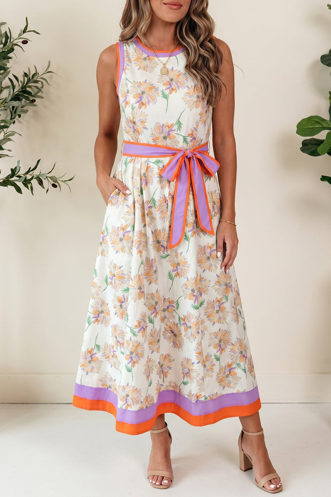 Daphne sleeveless floral maxi dress in white with orange and purple floral pattern, featuring a removable waist tie and side pockets.