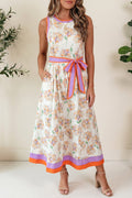Daphne sleeveless floral maxi dress in white with orange and purple floral pattern, featuring a removable waist tie and side pockets.