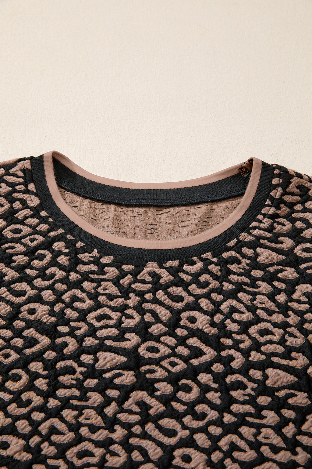 Close-up of a black and beige patterned sweater on a beige background