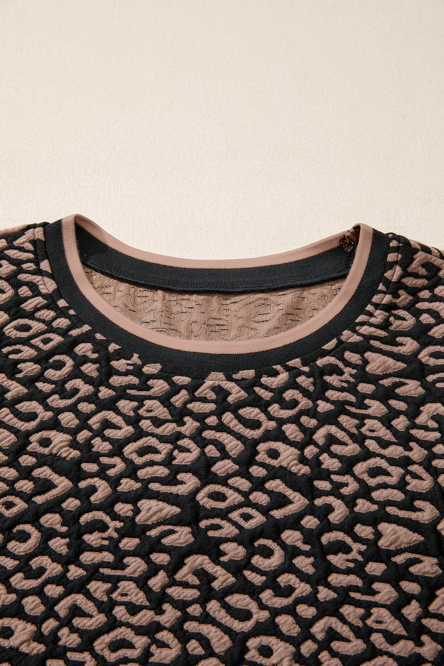Close-up of a black and beige patterned sweater on a beige background