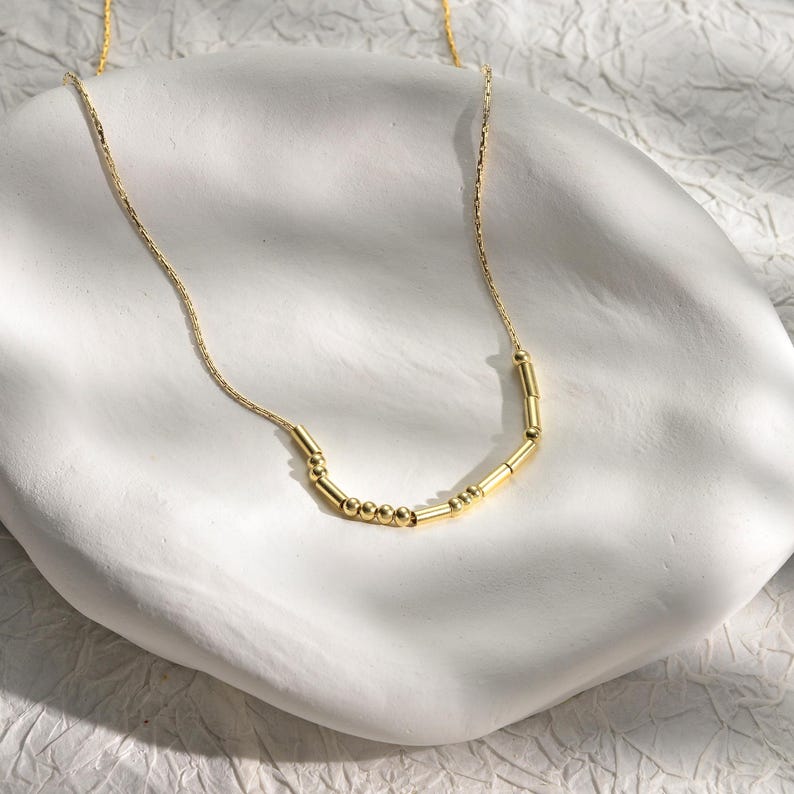 Elegant gold minimalist Morse code custom name necklace worn on a model.