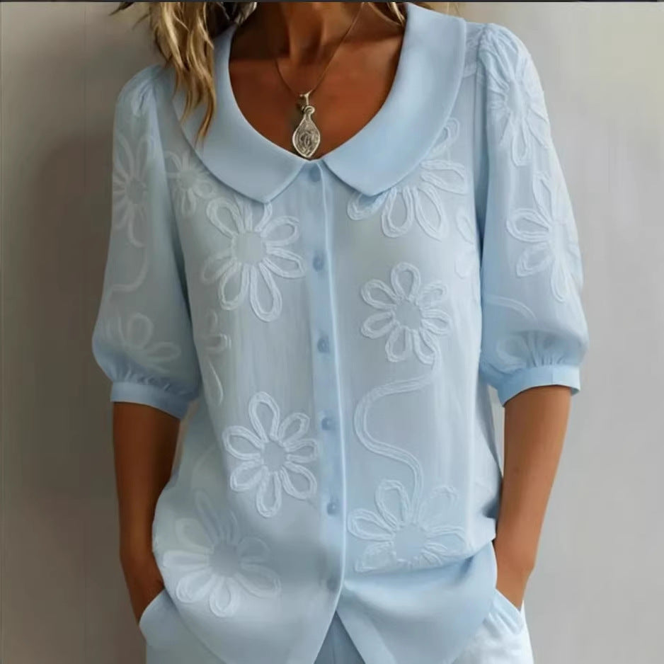 A woman wearing a loose-fit retro style shirt with 3D floral embroidery, featuring a round collar and button-down front.