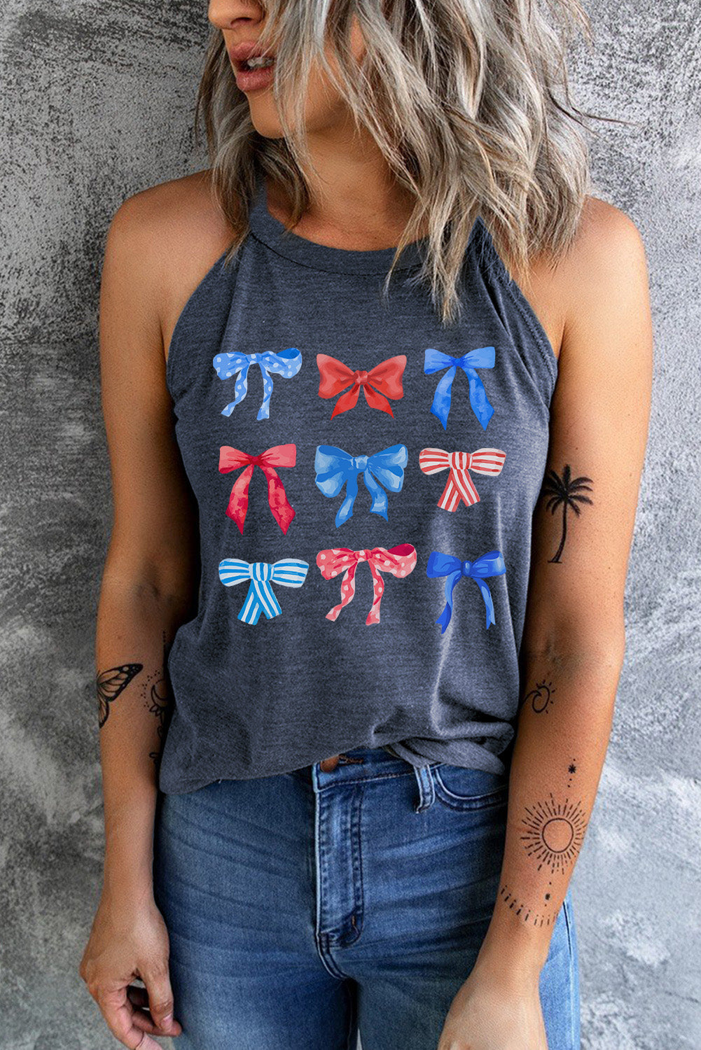 A woman wearing a charcoal grey tank top with a multi-colored bow graphic print on the front.