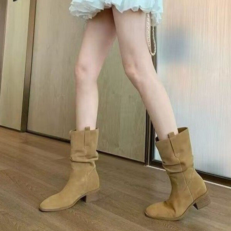 Tan cowhide leather western-style short boots with pleated detailing worn with a skirt