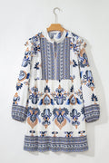 White, blue, and brown bohemian print mini dress with long sleeves and a split neckline.