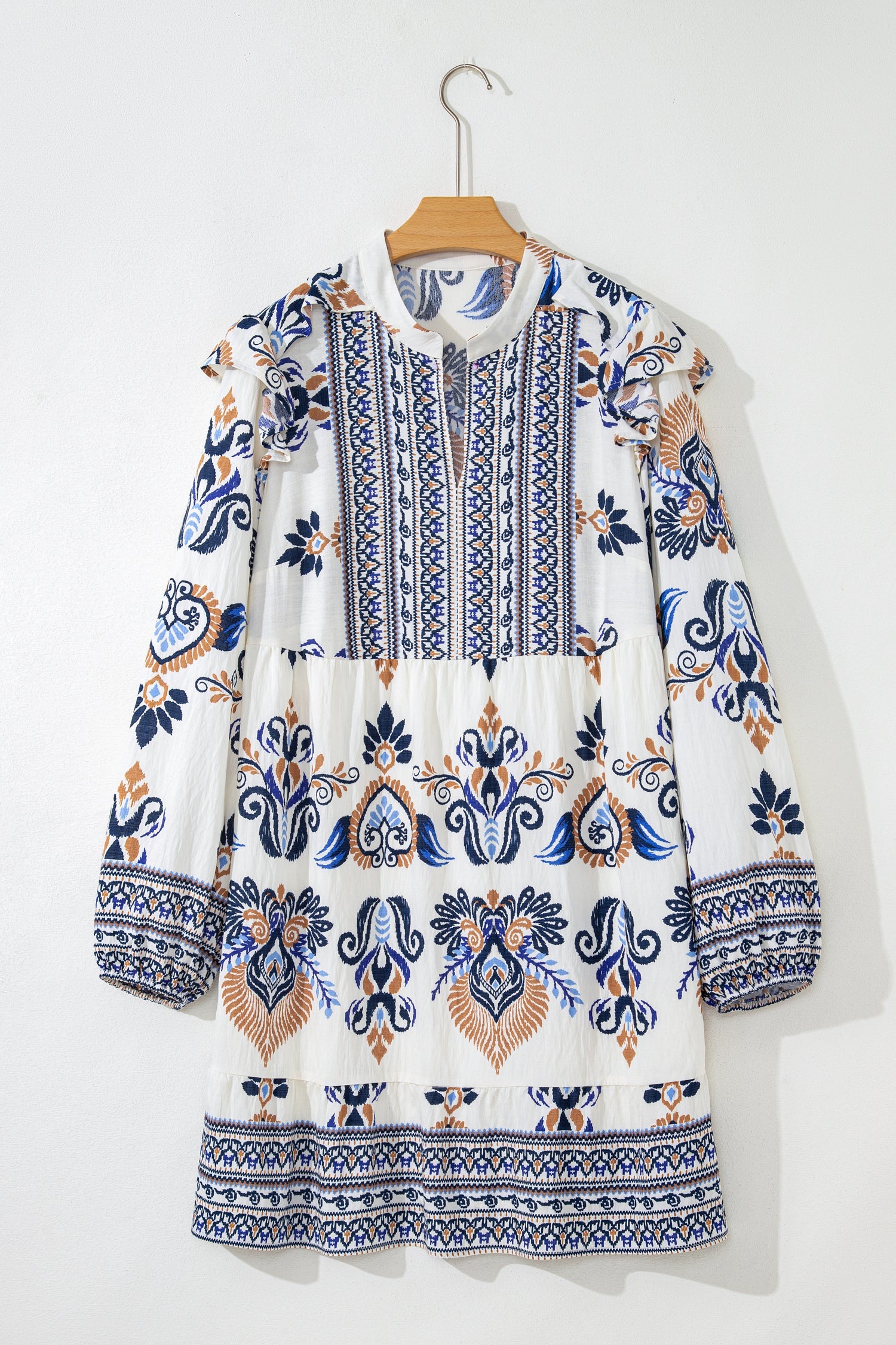 White, blue, and brown bohemian print mini dress with long sleeves and a split neckline.