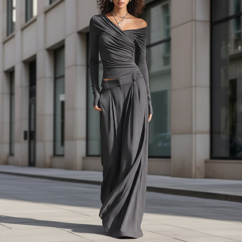 A woman wearing a charcoal grey two-piece set featuring an off-shoulder long-sleeve top and matching wide-leg trousers.