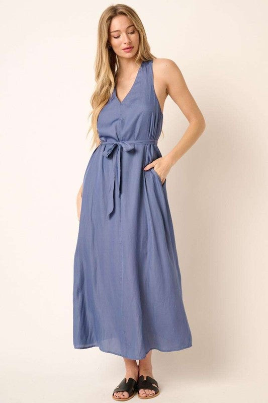 Model wearing a flattering V-neck tank maxi dress with a belted waist and unique cross-back detail.