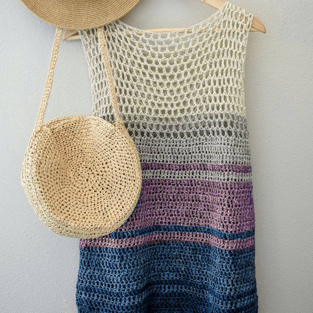Woman wearing a sleeveless bohemian crochet top with a beige-to-blue ombre pattern on a beach.
