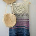 Woman wearing a sleeveless bohemian crochet top with a beige-to-blue ombre pattern on a beach.