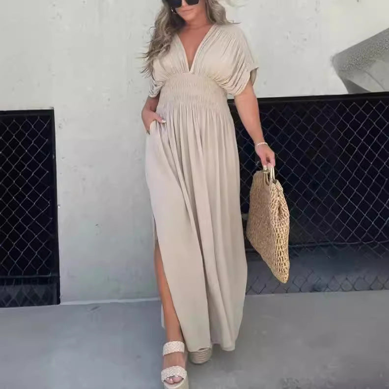 Woman wearing a solid black V-neck maxi dress with bat-wing sleeves and a side slit