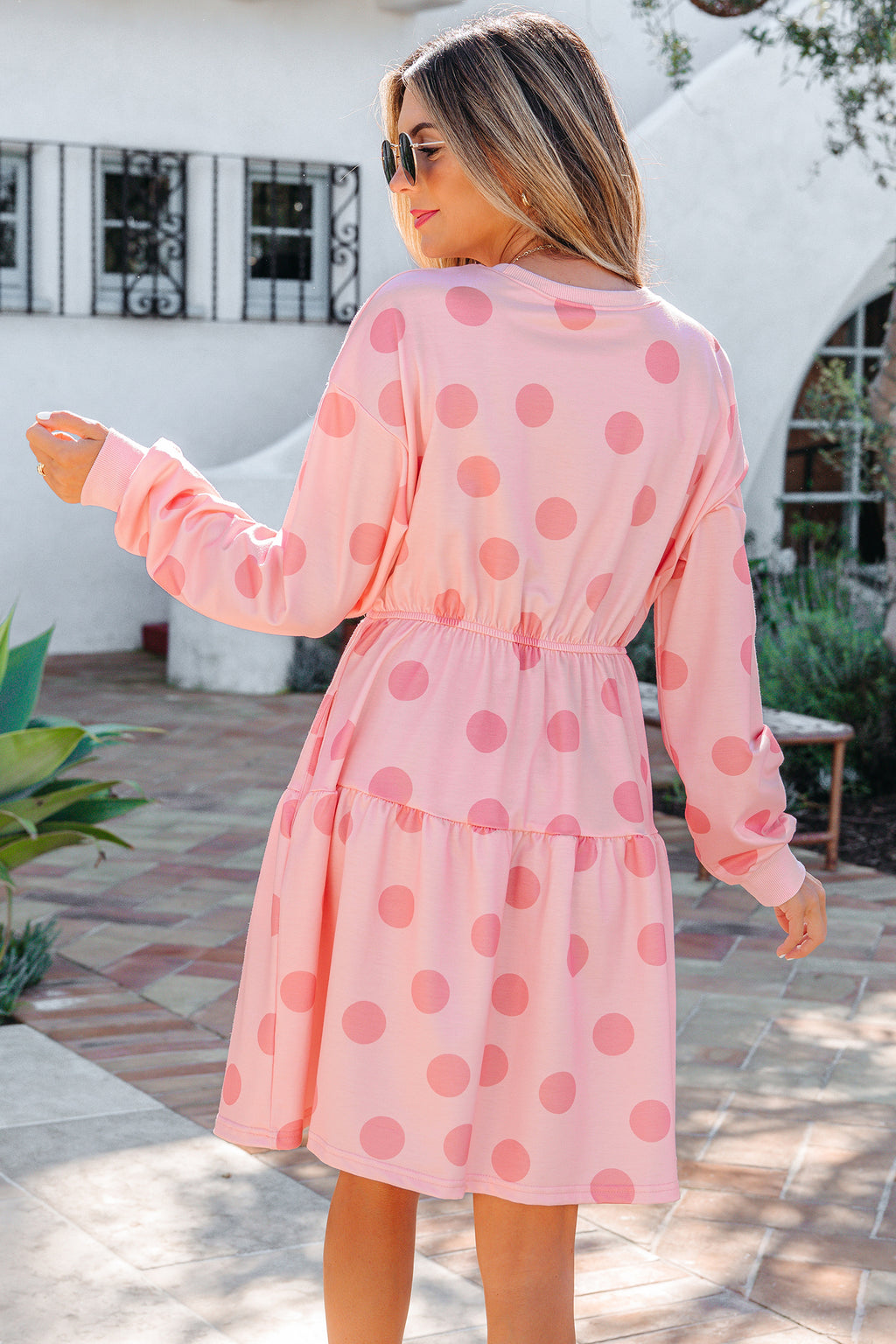 Back view of model wearing pink polka dot dress