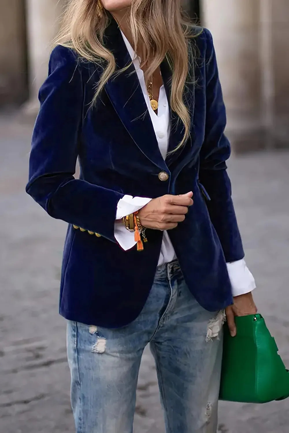 Model wearing a navy blue velvet single-button blazer with lapel collar over a white shirt and distressed jeans.