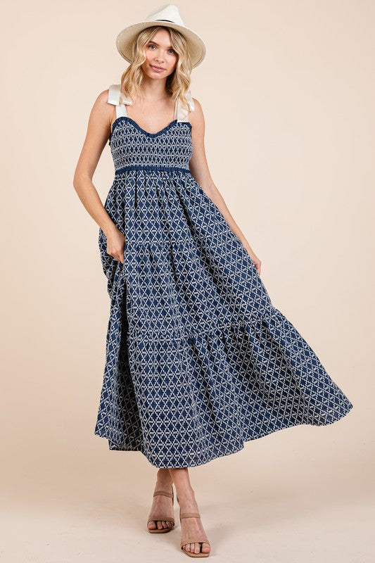 Woman wearing a geometric embroidered midi dress with smocked bodice and tie shoulder details