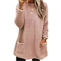 A woman wearing a cozy long-sleeve blush-colored fuzzy fleece dress with two front pockets.