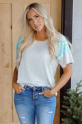 Model wearing a white and grey striped round neck t-shirt with floral print panel sleeves.