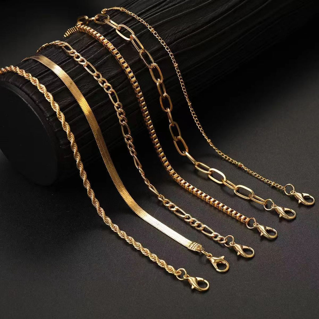 Multi-layer Figaro chain minimalist bracelet in gold and silver tones on a white background.