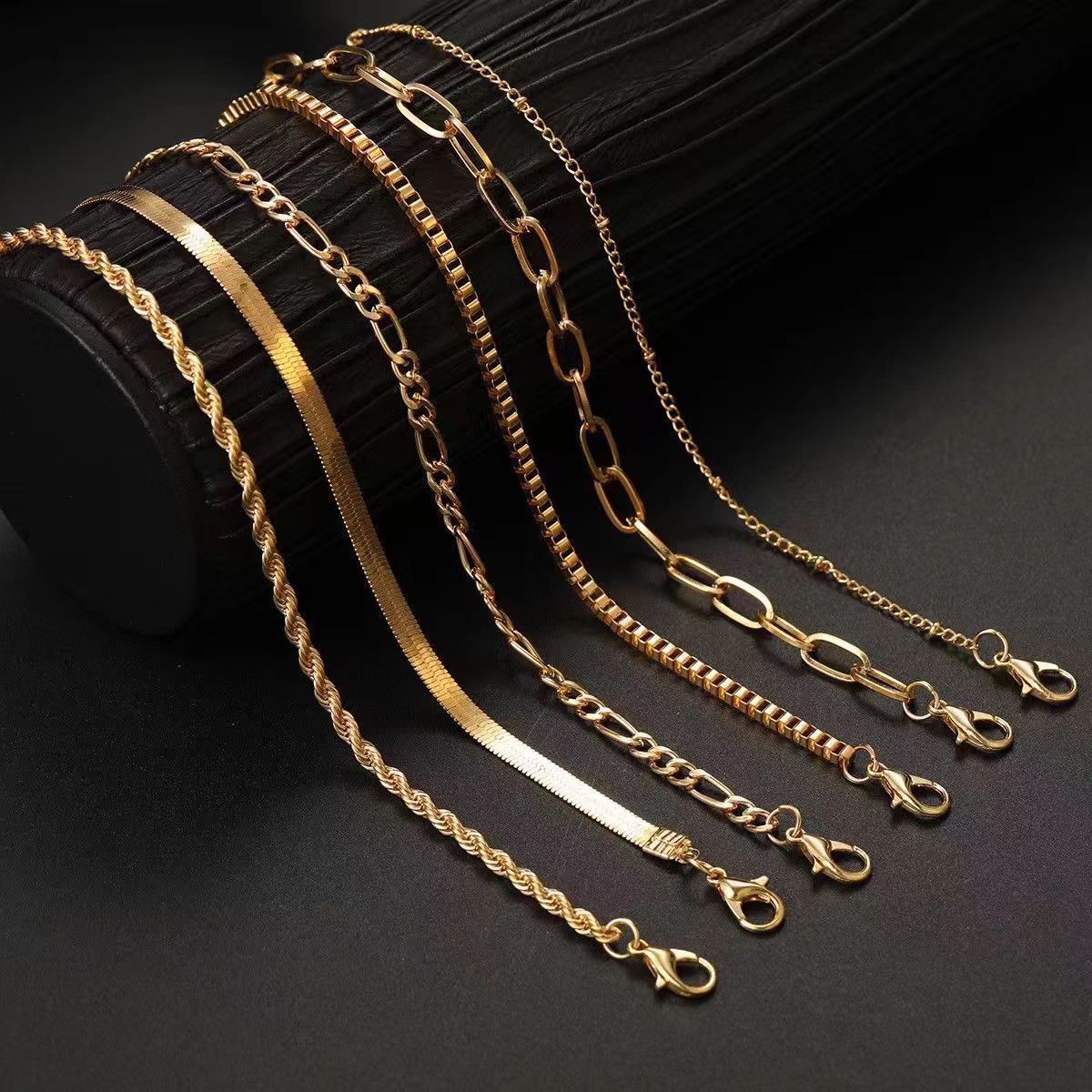 Multi-layer Figaro chain minimalist bracelet in gold and silver tones on a white background.