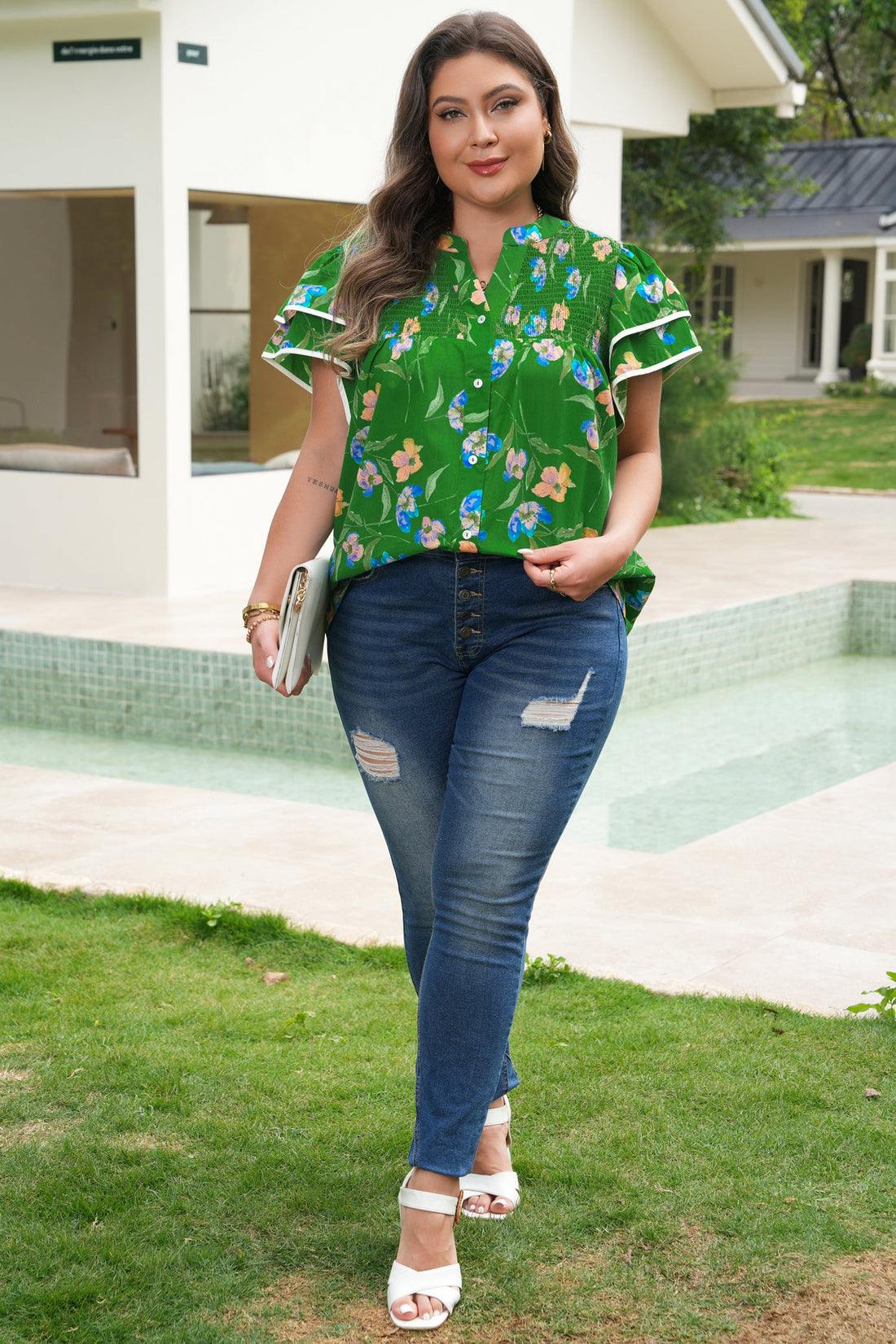 Woman wearing a floral print cotton short sleeve blouse with flutter sleeves and buttons.