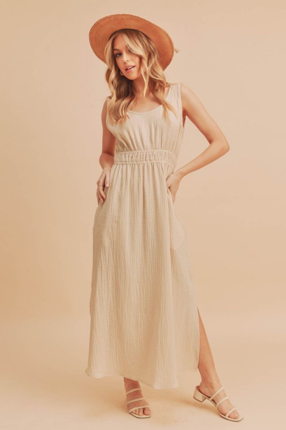 A beige sleeveless maxi tank dress with side slits and a round neckline.