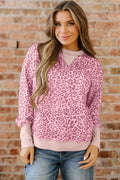 Front and back view of a woman wearing a pink leopard print patchwork sweatshirt with a crew neckline.