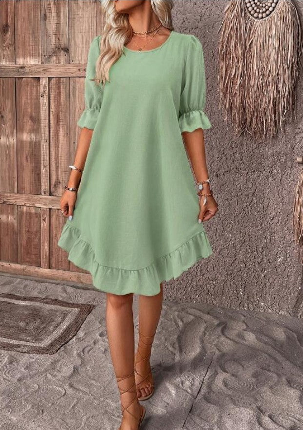 Woman wearing a bohemian style loose straight-fit olive green cotton linen ruffle dress with short sleeves
