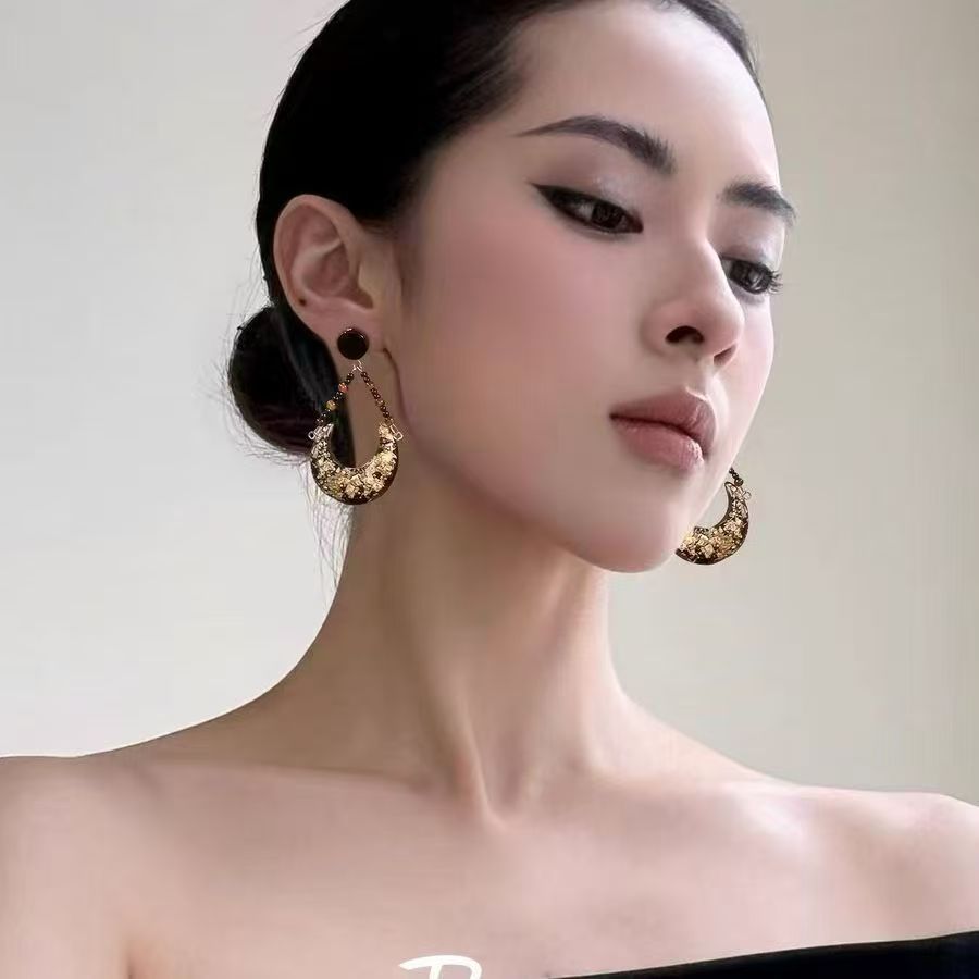 Retro black and gold moon stud earrings with intricate beadwork.
