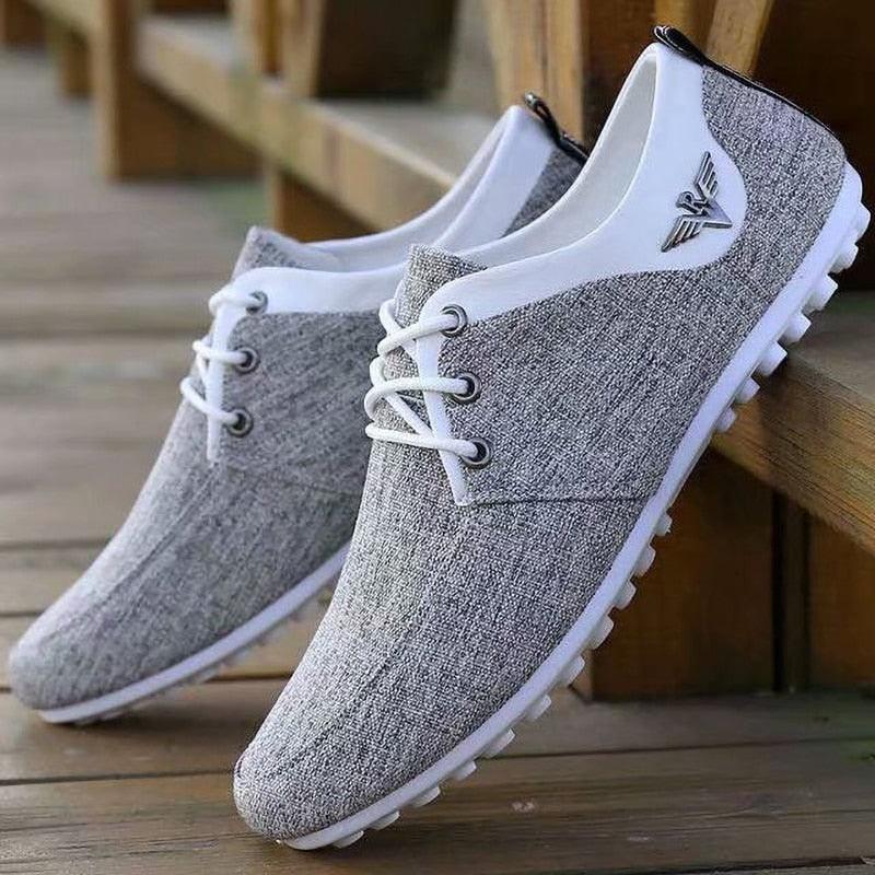 A pair of minimalist men's linen lace-up sneakers in neutral grey and white, ideal for casual summer styling.