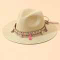 Elegant straw bucket hat with tassel detail, available in beige and black for summer beach travel.