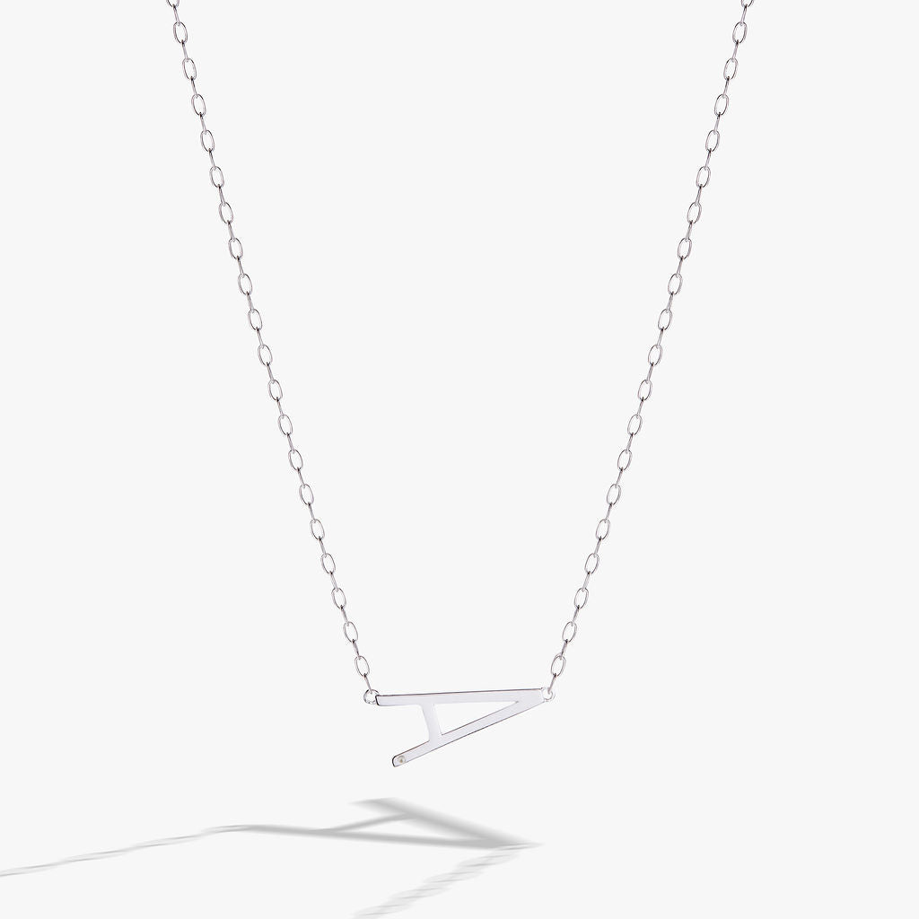 Delicate sideways letter A initial pendant necklace in gold, accented with a small cubic zirconia stone.