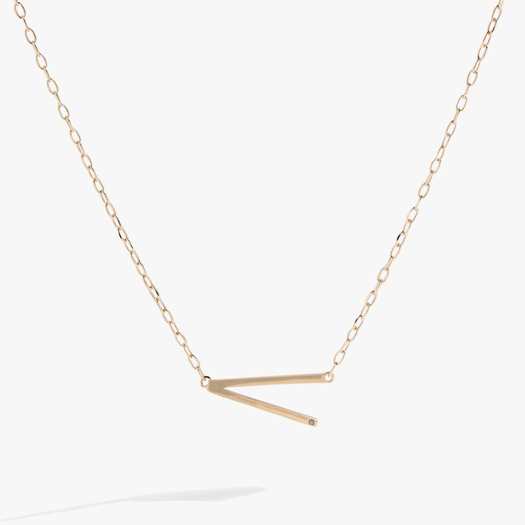 Sideways initial V pendant necklace with cubic zirconia in gold or silver.