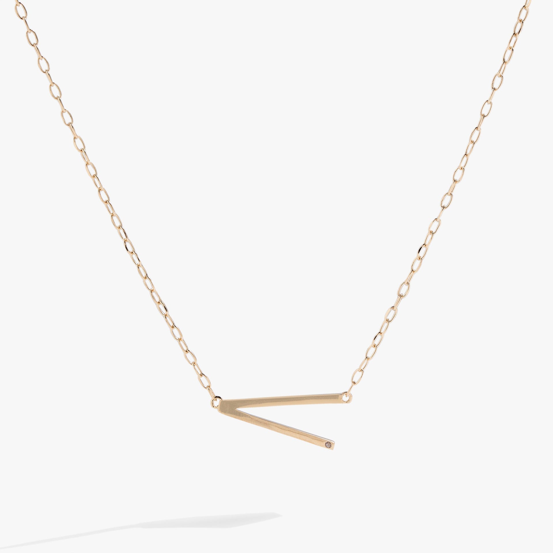 Sideways initial V pendant necklace with cubic zirconia in gold or silver.
