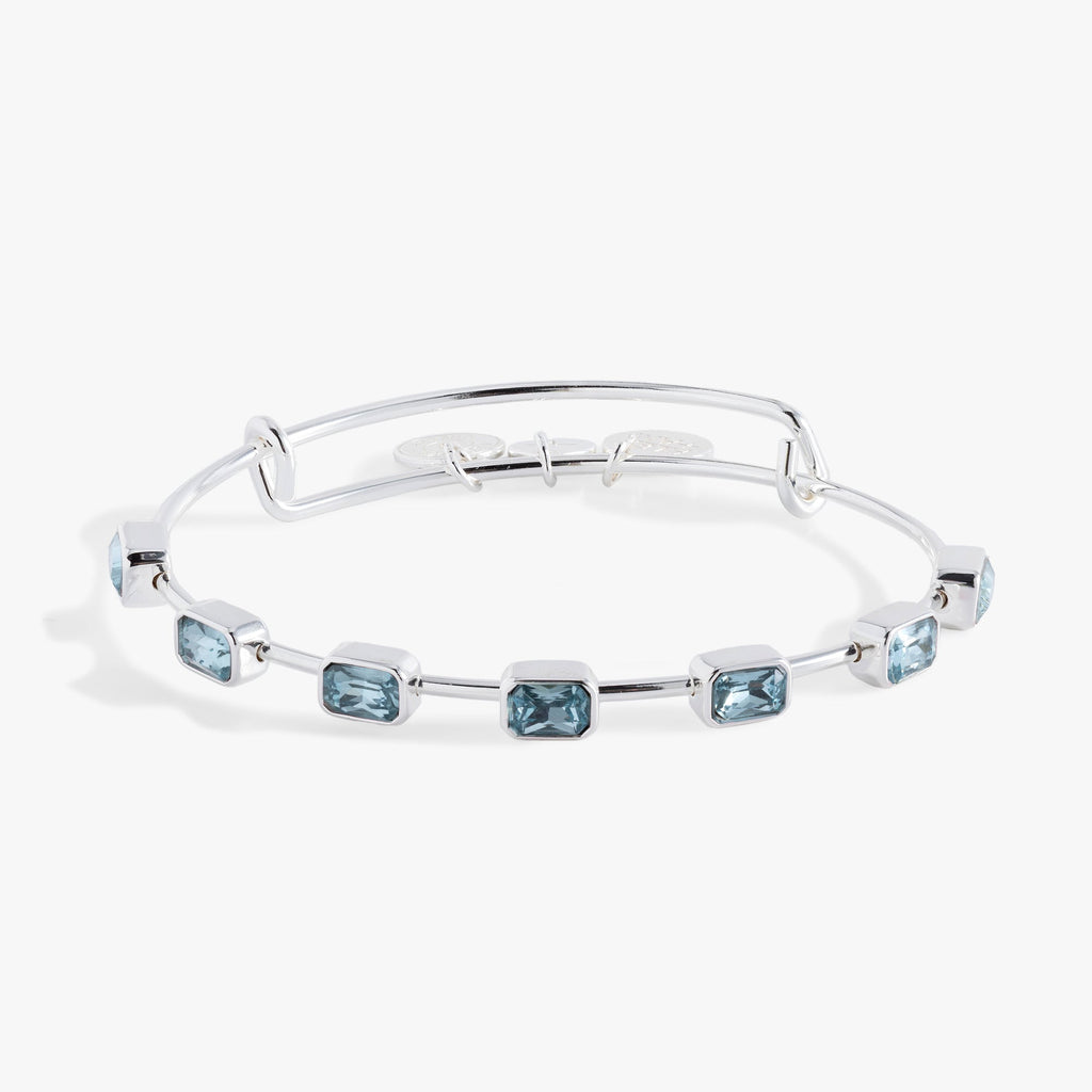 March birthstone bangle with seven aquamarine blue emerald-cut crystals on an expandable wire band.