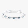March birthstone bangle with seven aquamarine blue emerald-cut crystals on an expandable wire band.