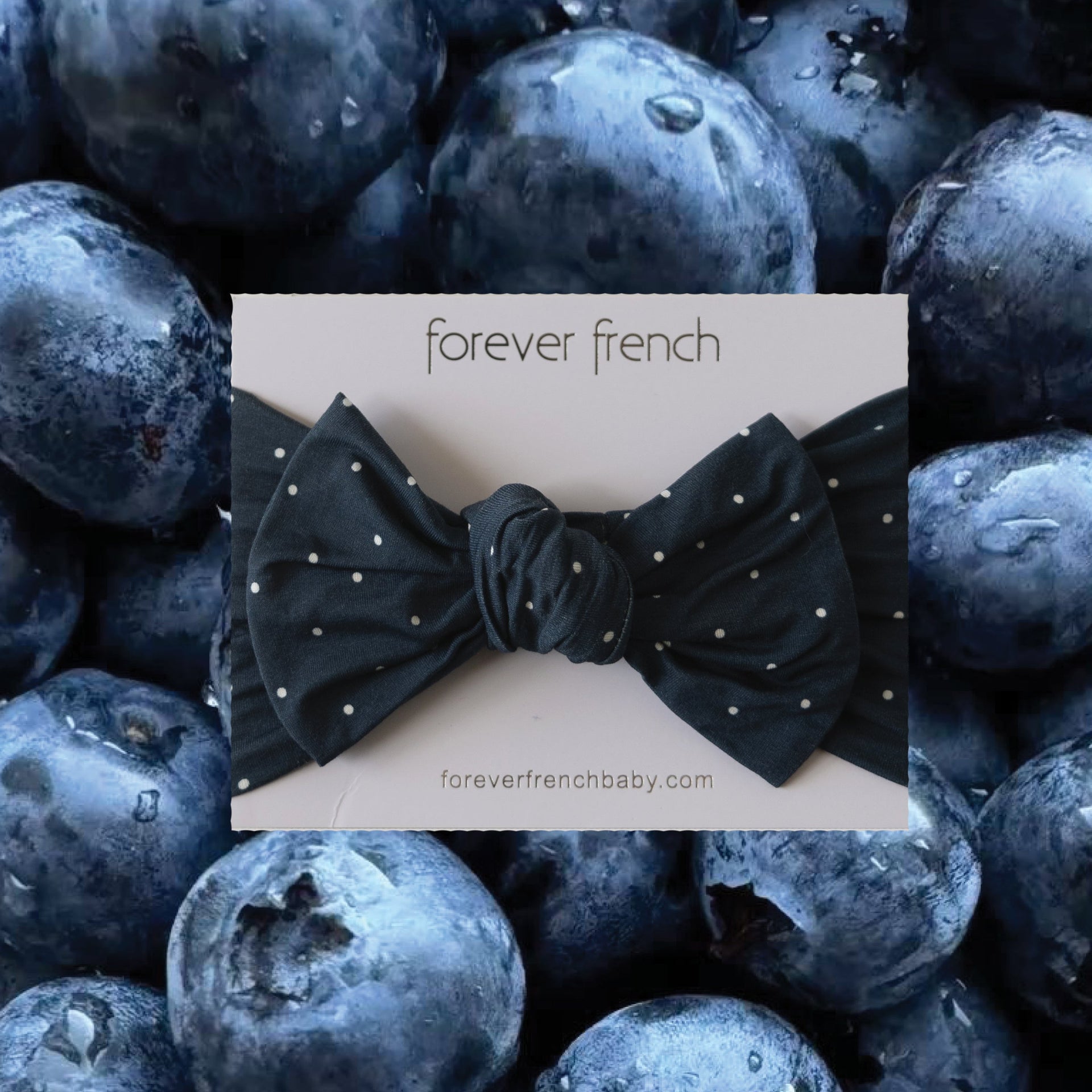 Baby head wrap in navy blue with cream polka dots and a sweet bow detail