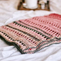 Finished En Rose Lap Blanket draped over an armchair featuring intricate crochet stitchwork