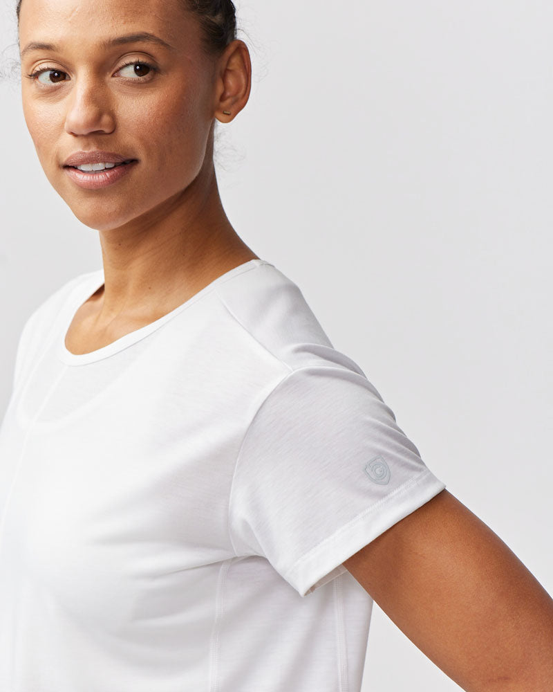A woman wearing a white short-sleeve performance t-shirt performing a kettlebell workout.