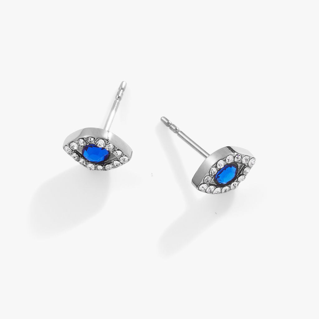 Minimalist silver Evil Eye stud earrings with sapphire blue and clear crystal accents.